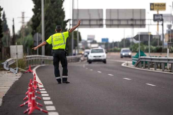 Un agente de la Guardia Civil de Tráfico da el alto a un conductor en un control