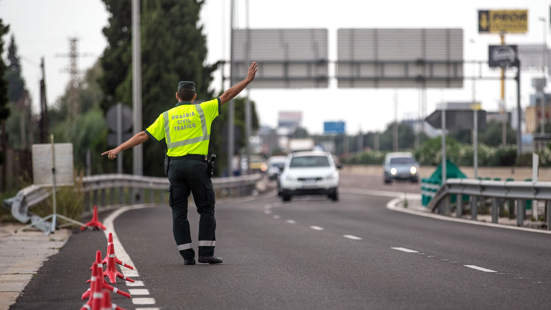 Un agente de la Guardia Civil de Tráfico da el alto a un conductor en un control
