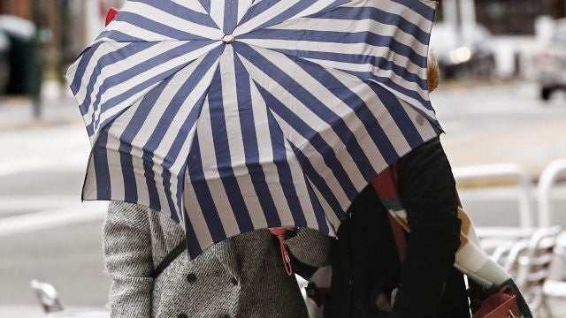 Dos mujeres se protegen con un paragüas de la lluvia y el viento 