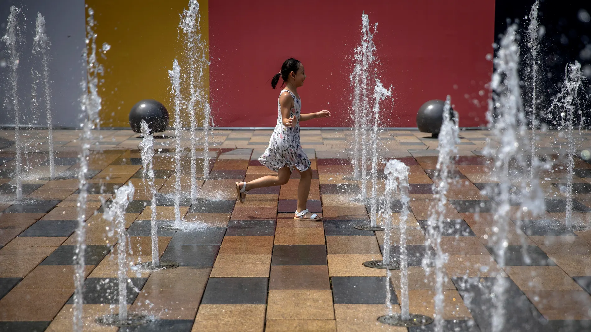 A child plays in a fountain in the Sanlitun area of Beijing, China