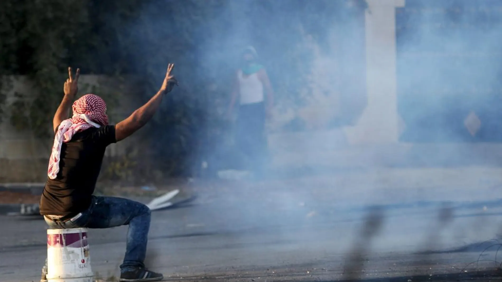 Un manifestante palestino se protege del gas lacrimógeno lanzado por las tropas israelíes cerca del asentamiento judío de Beit El, cerca de Ramala