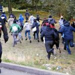 Un grupo de emigrantes huye de los policías franceses en Calais antes de intentar tomar un tren a Reino Unido