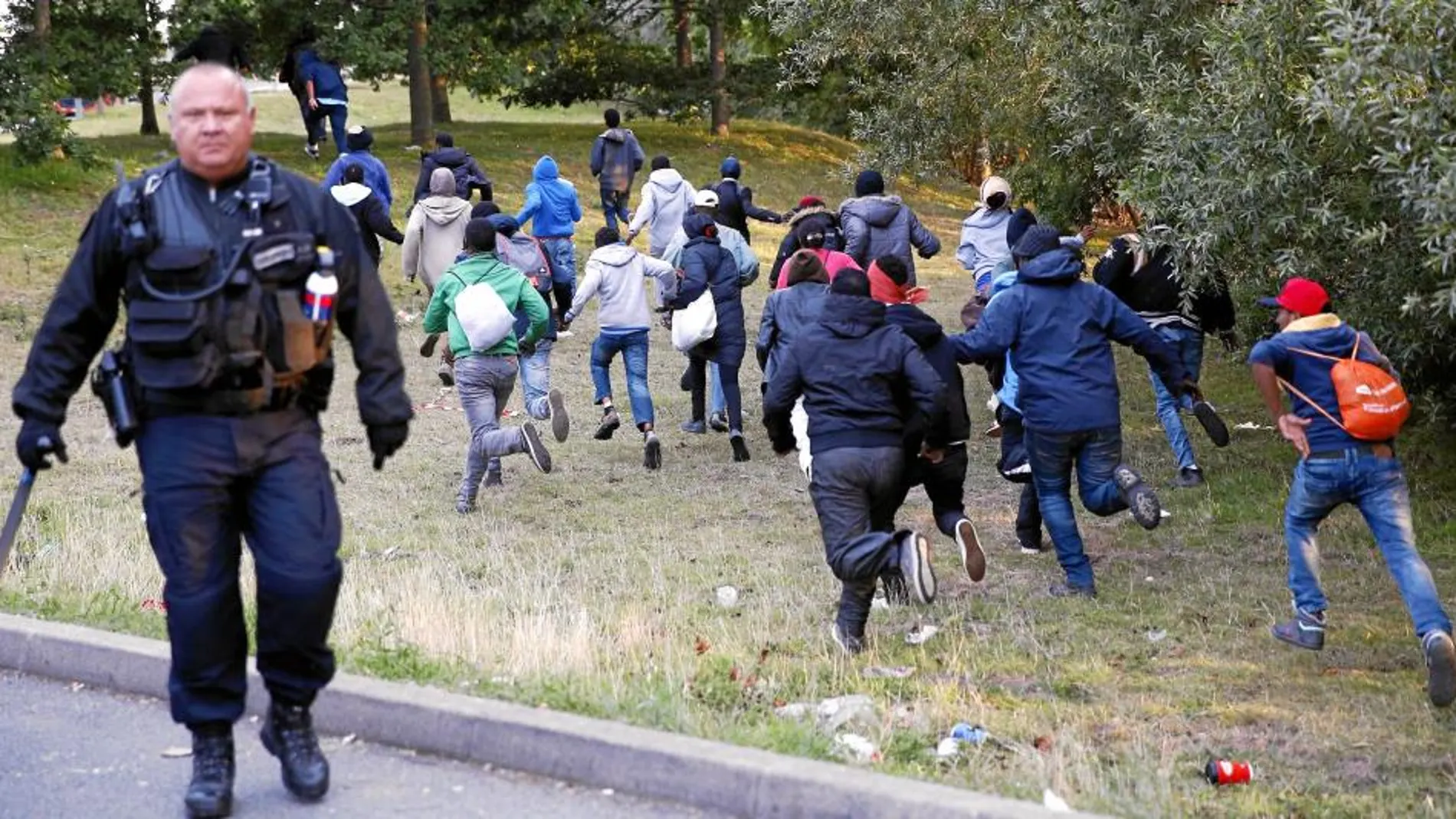 Un grupo de emigrantes huye de los policías franceses en Calais antes de intentar tomar un tren a Reino Unido