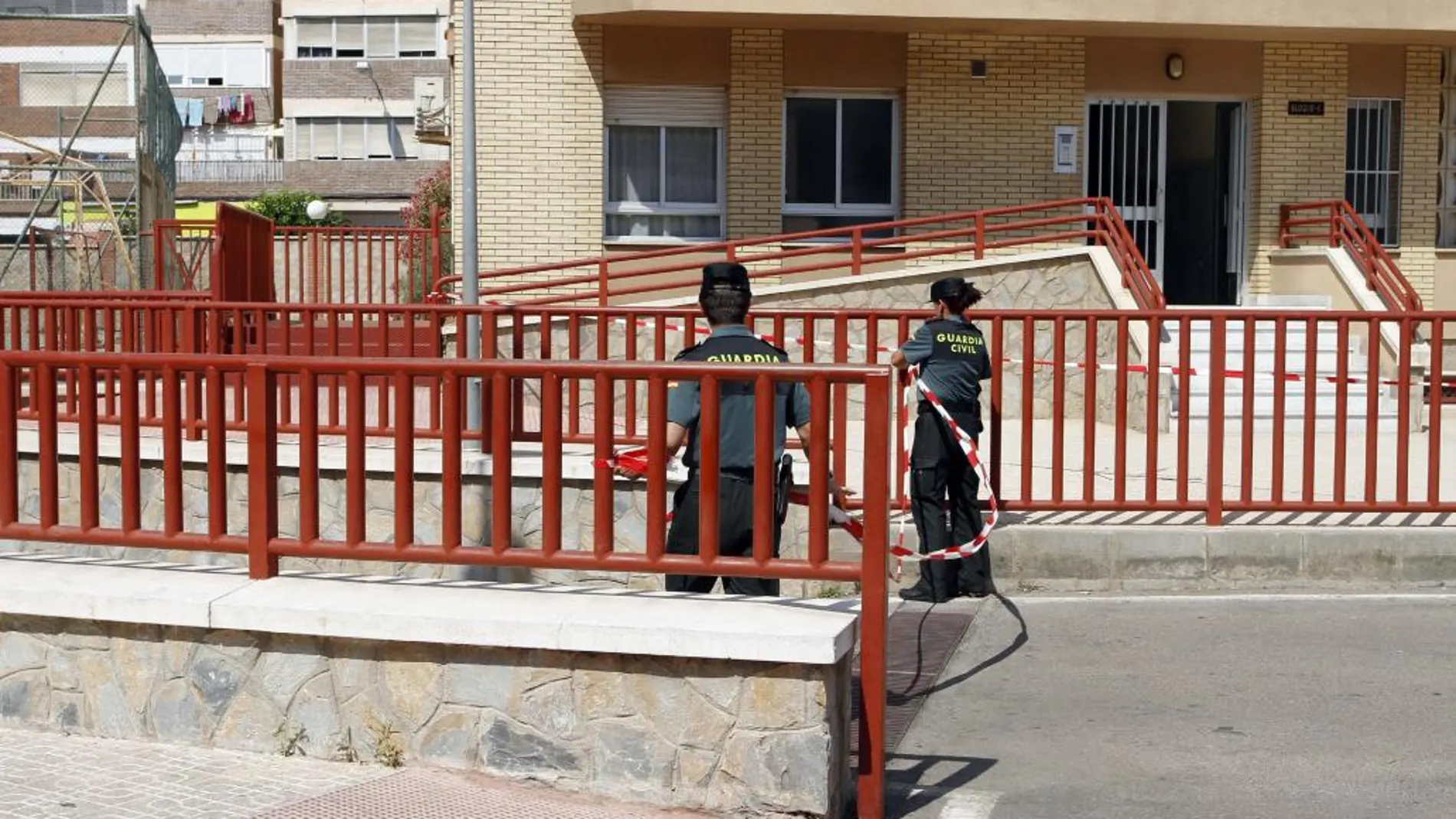 Dos guardias civiles colocan una cinta para impedir el paso en la entrada de las cocheras donde el pasado miércoles murió un miembro de los Tédax