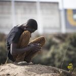 Un inmigrante se sienta de cuclillas en el campamento conocido como "la jungla"junto a la carretera en Calais