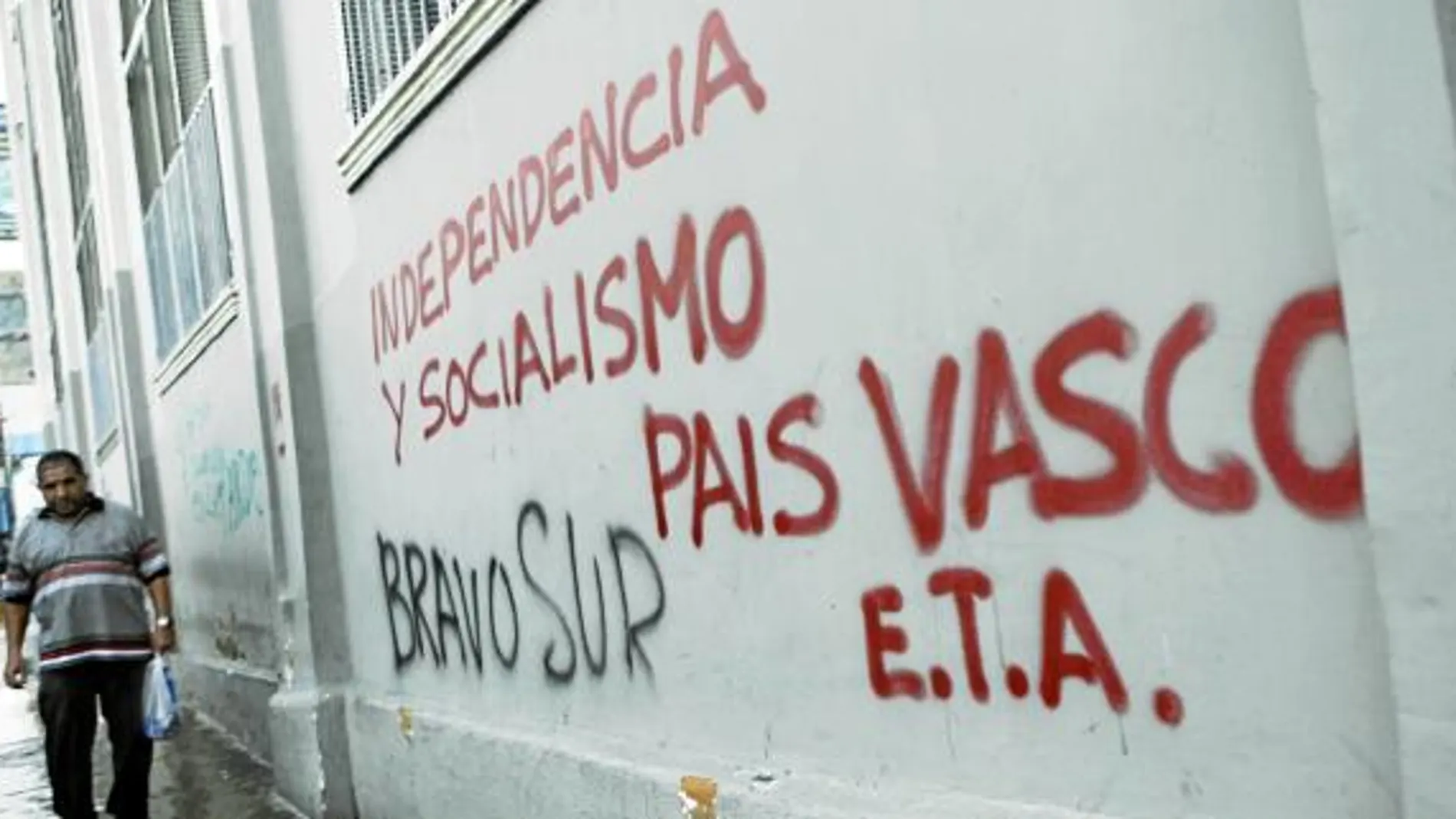 Un hombre camina en una calle de Caracas junto a una pintada que reclama la independencia del País Vasco