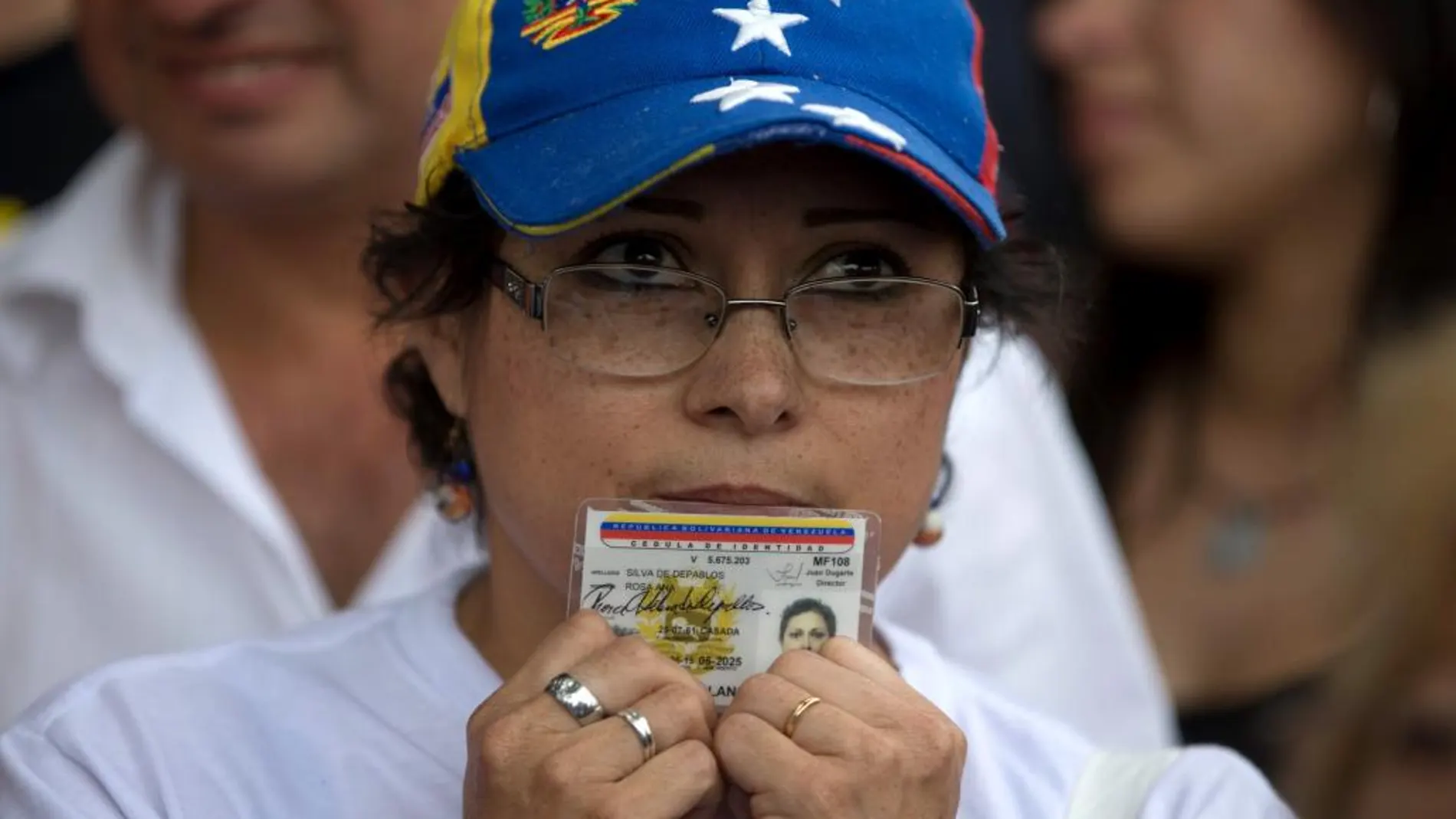 Una mujer sostiene su identificación para firmar la petición de un referéndum revocatorio contra Nicolás Maduro.