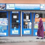 Imagen de una mujer musulmana pasando por delante de la puerta del locutorio de Ripoll, vinculado con los ataques de Barcelona y Cambrils, con una bombona de butano