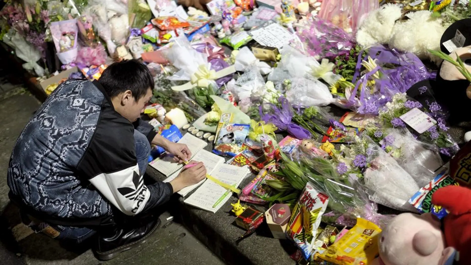 Un hombre escribe un mensaje junto al improvisado altar donde murió la niña