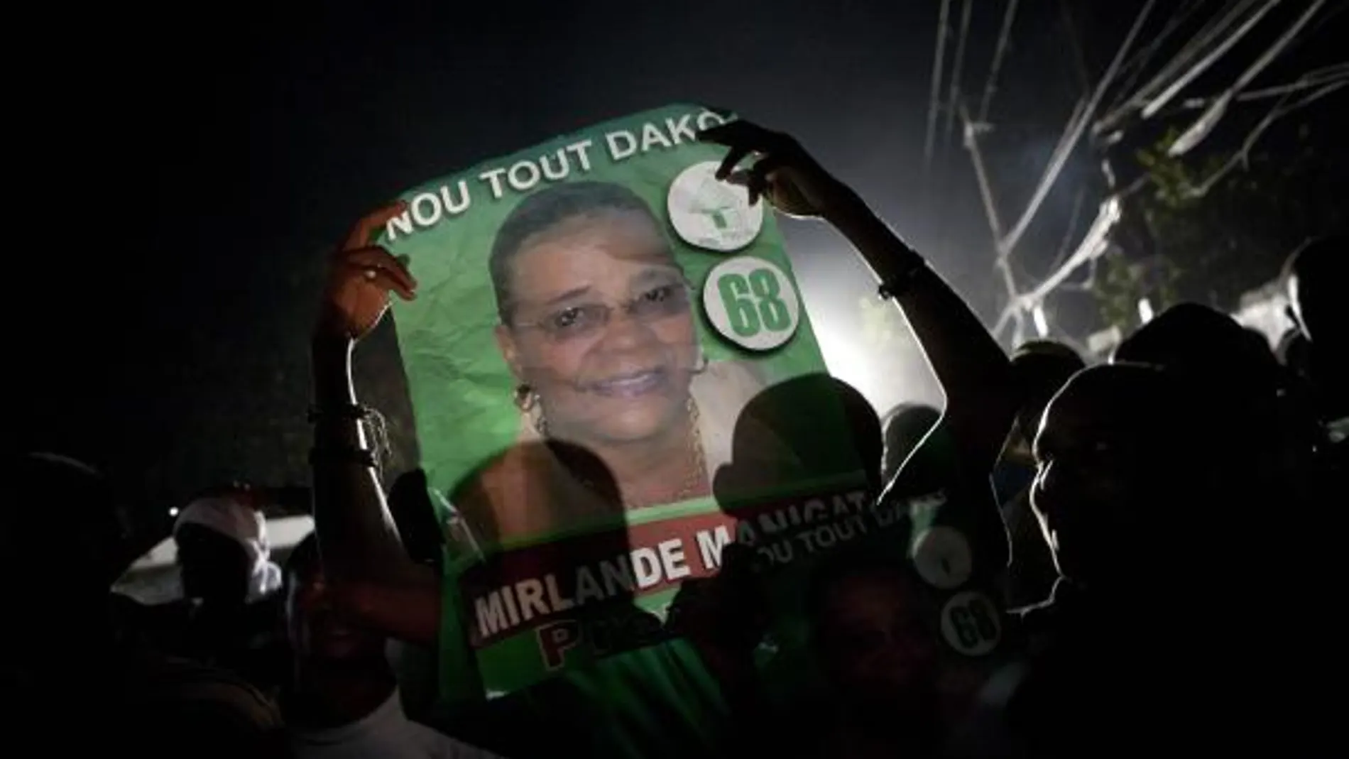 Seguidores sostienen carteles electorales de la candidata presidencial Mirlande Manigat