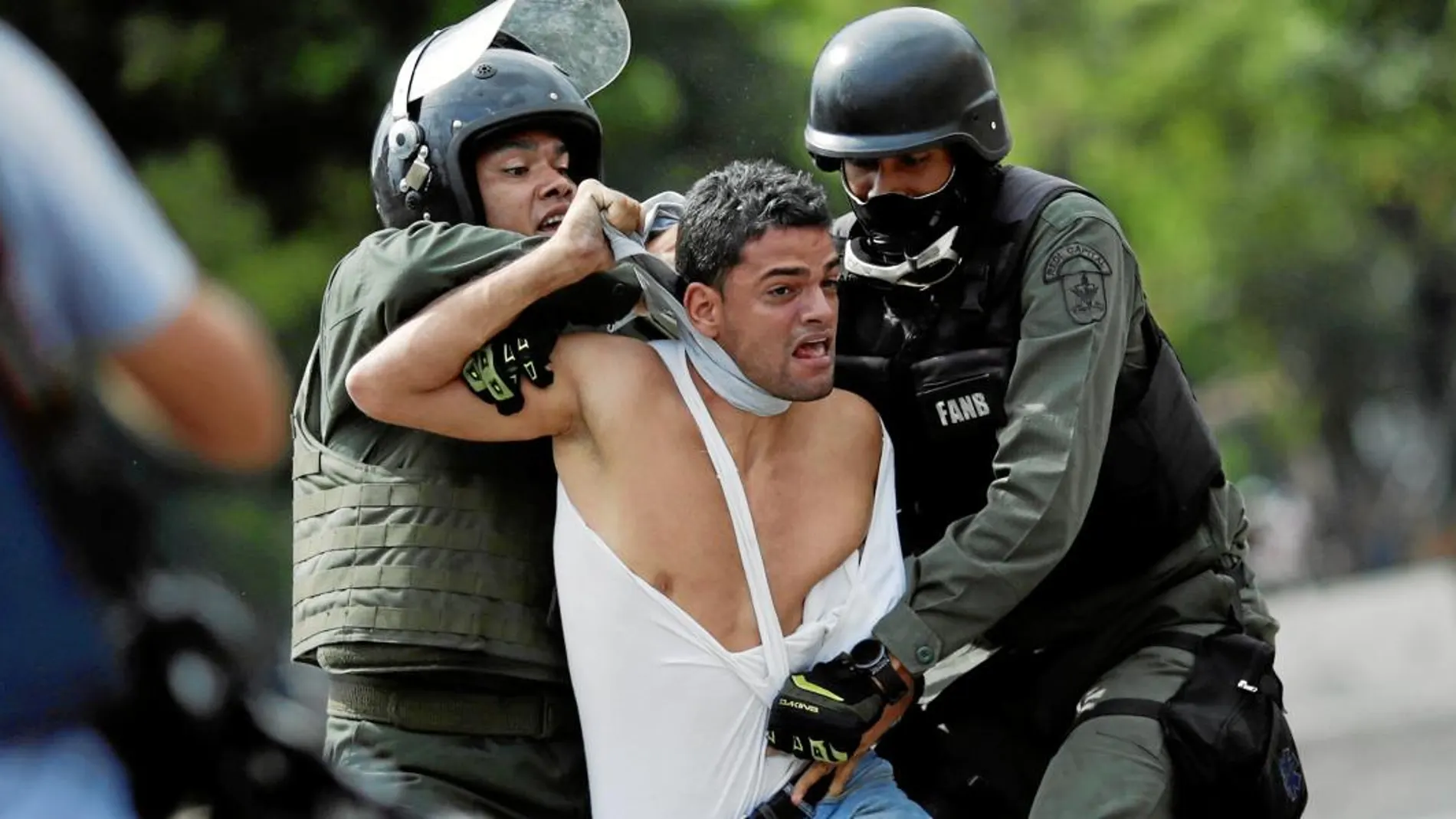 En Venezuela impera la ley del plomo, con un Estado ausente que mira para otro lado e incluso perpetra matanzas. En la imagen, un joven es detenido durante las protestas de julio
