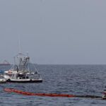 Dos barcos pesqueros colocan una barrera resistente al fuego antes de realizar una quema controlada de crudo en el Golfo de México