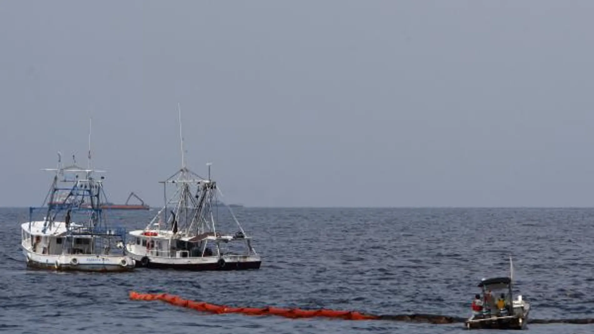 Dos barcos pesqueros colocan una barrera resistente al fuego antes de realizar una quema controlada de crudo en el Golfo de México