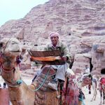 Un conductor de camello en Petra lee el nuevo modelo de mapa turístico