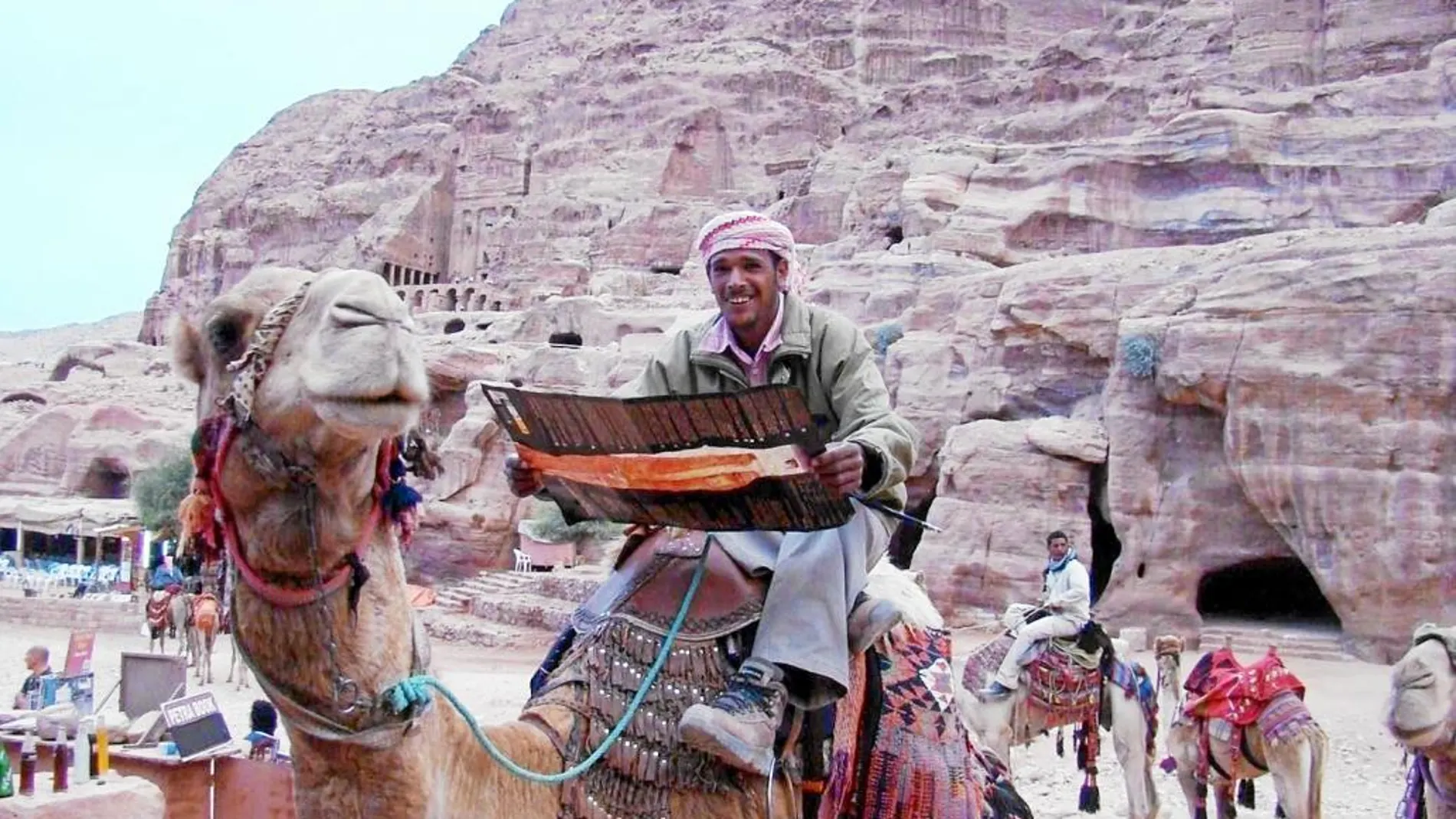 Un conductor de camello en Petra lee el nuevo modelo de mapa turístico