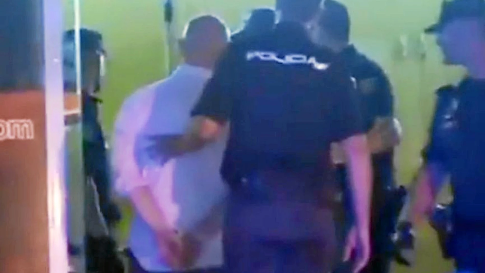 Uno de los acusados, esposado por la Policía Nacional