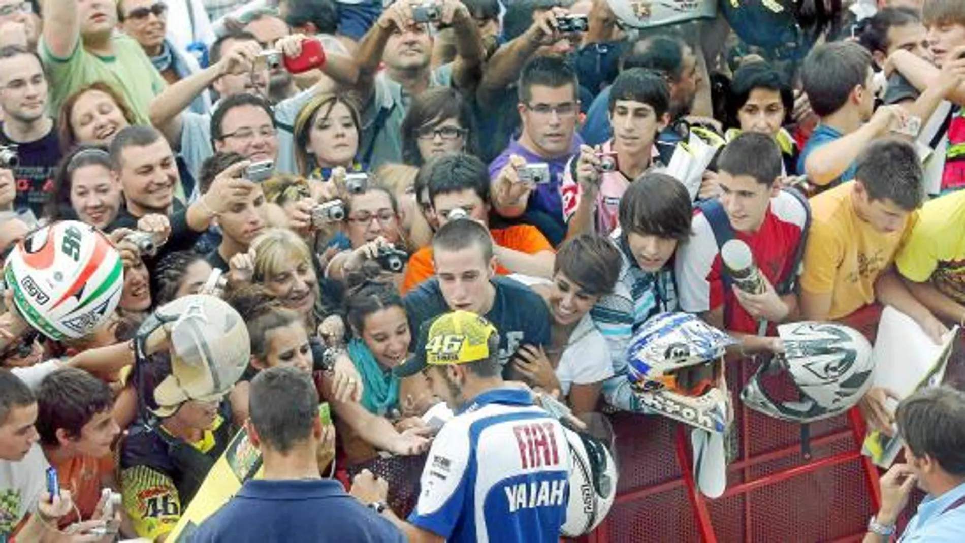 Valentino Rossi firma autógrafos a una multitud de aficionados en el «pit lane» del circuito de Motorland, en Alcañiz