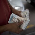 Un hombre cuenta billetes en una gasolinera de Caracas / Ap
