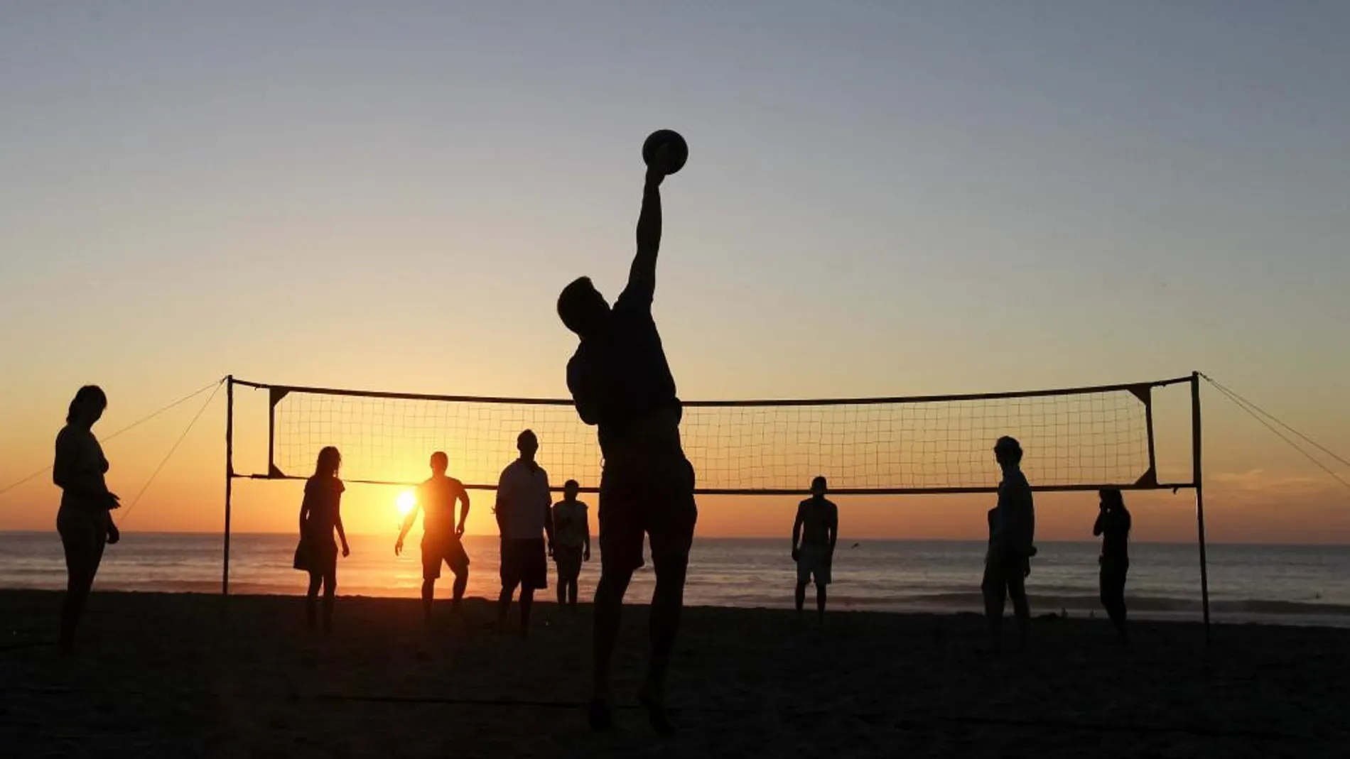 n grupo de jóvenes juega un partido de voleibol al atardecer de la playa de la Zurriola, en San Sebastián