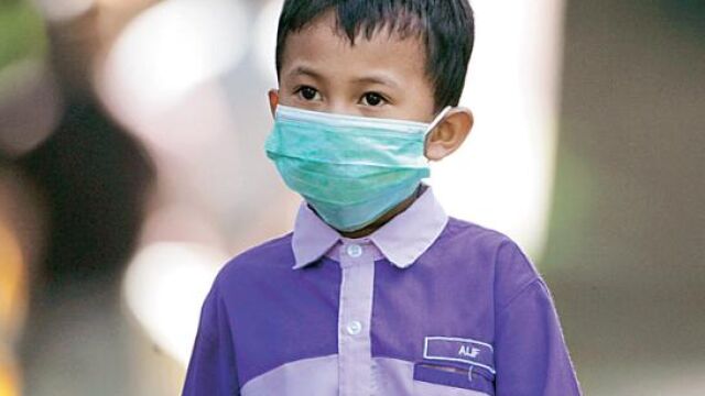 Un preescolar se protegía ayer de la gripe en Malasia