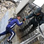 Un guardia civil ayuda a un menor a subir de la escollera en Melilla