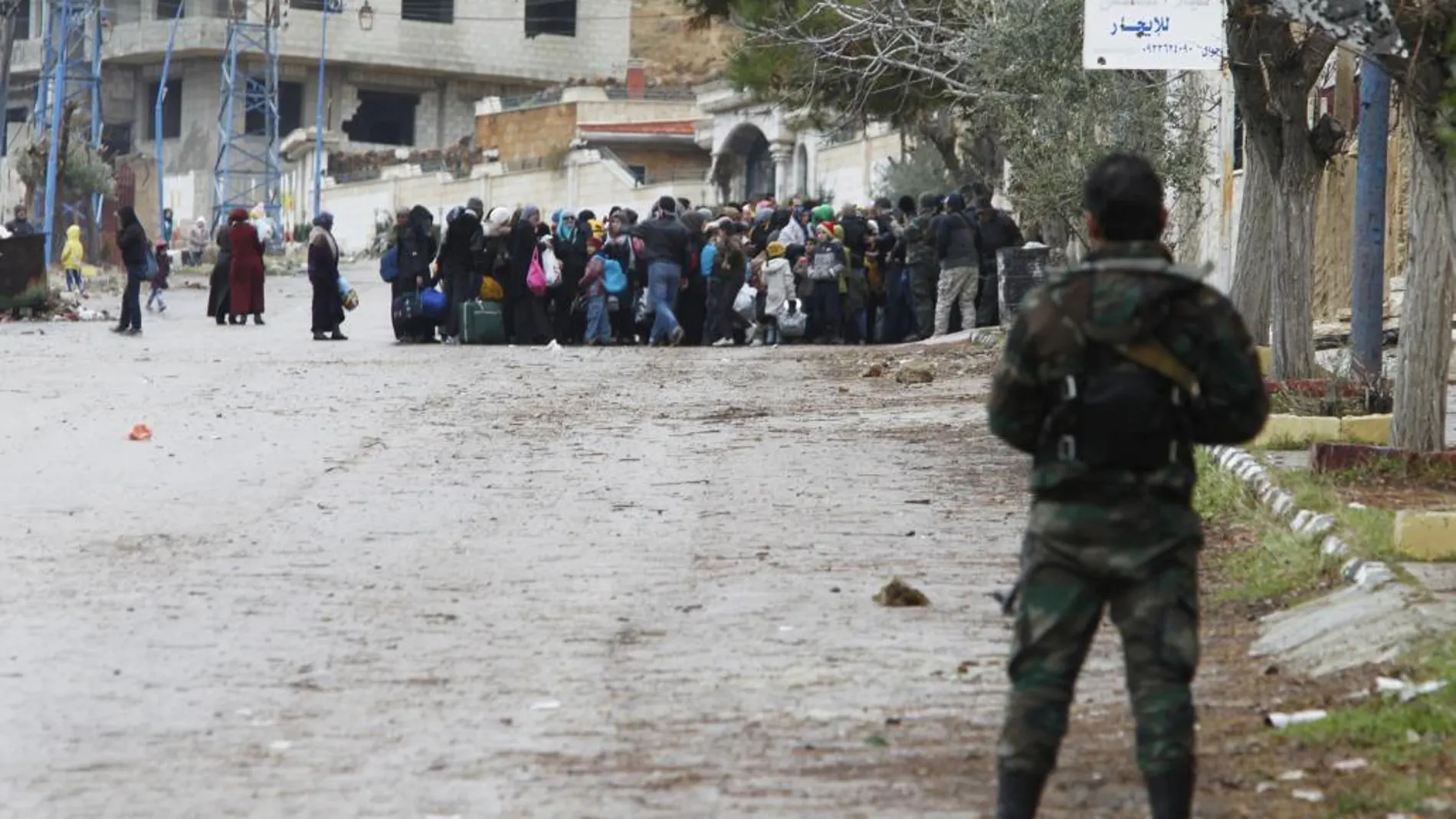 Soldados del ejército sirio vigilan a los residente autorizados a acudir a la zona de espera para recibir la ayuda humanitaria