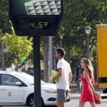 Dos personas pasan por delante de un termómetro en Zaragoza