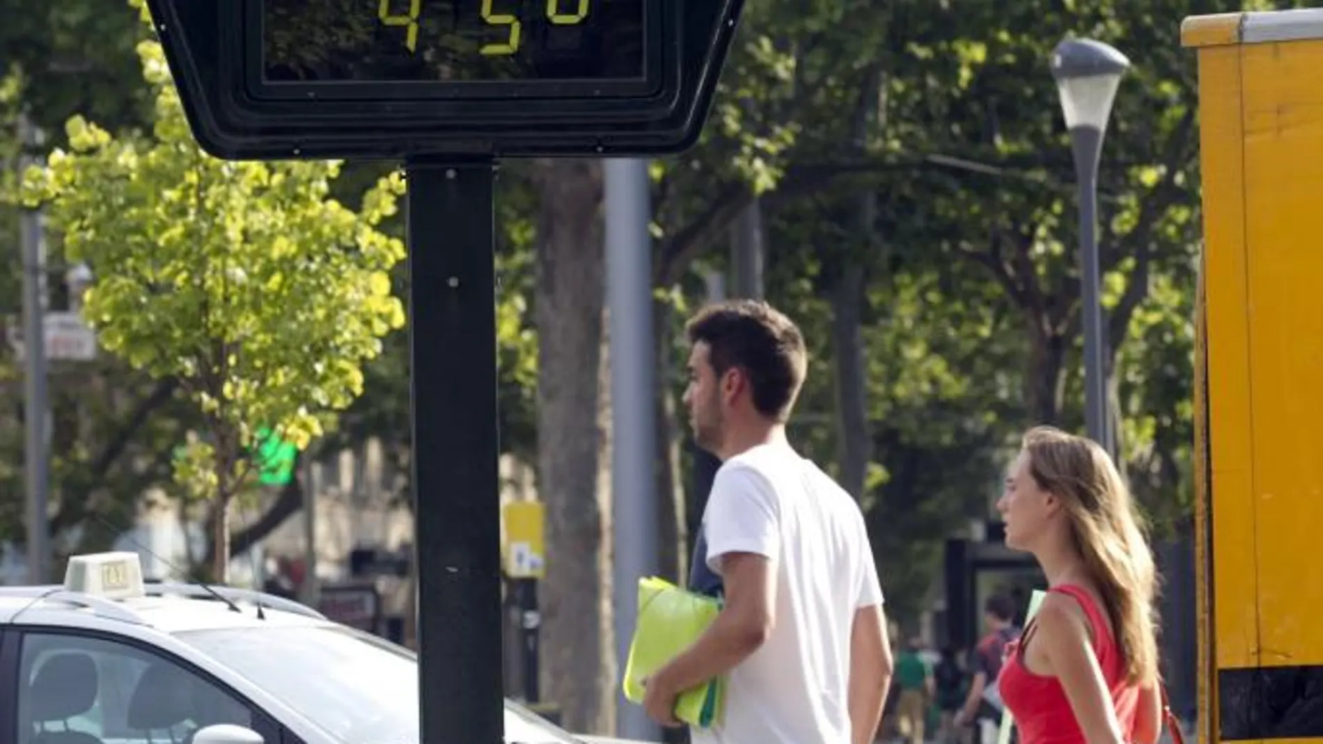 Dos personas pasan por delante de un termómetro en Zaragoza
