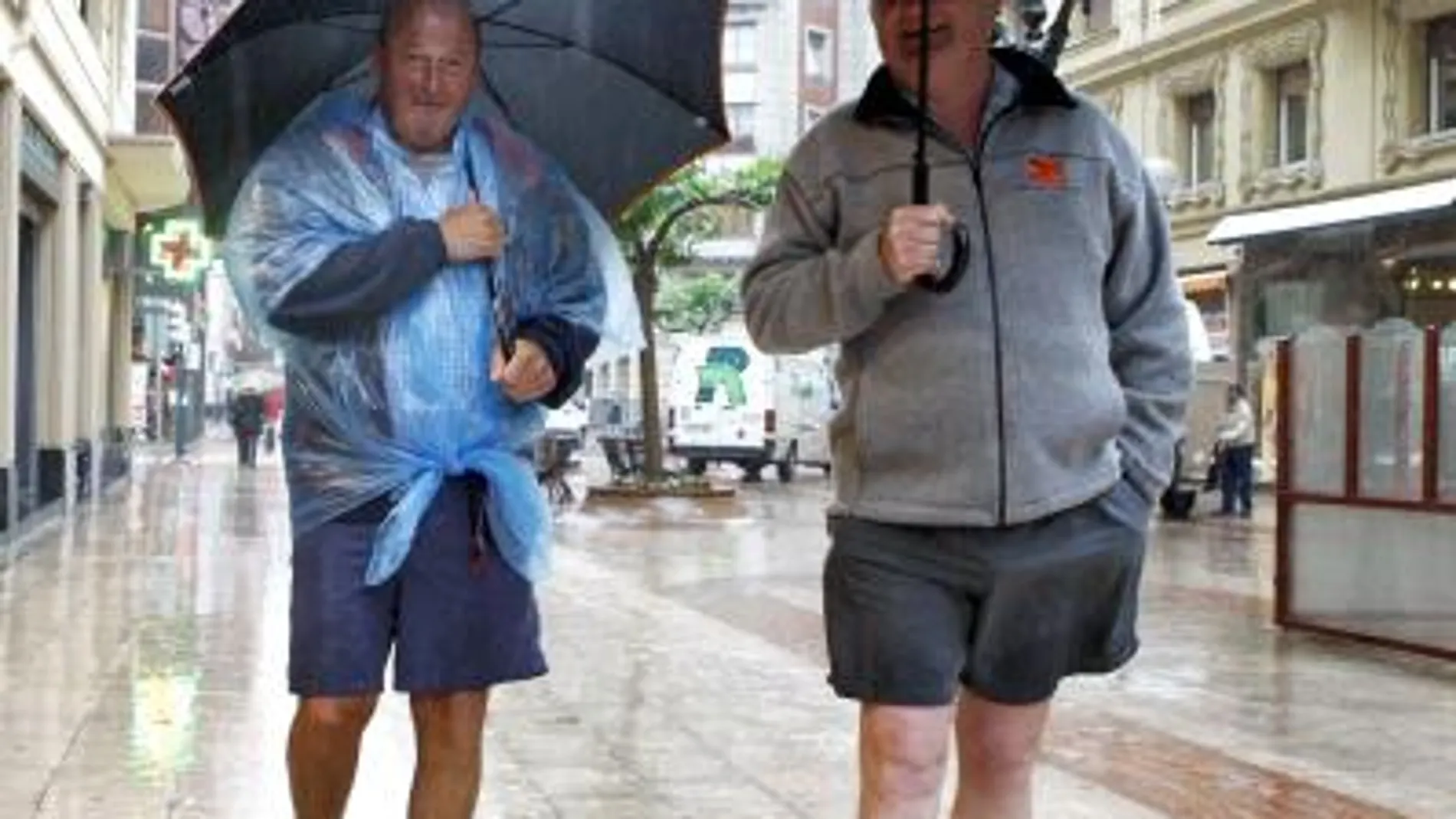 Dos turistas pasean bajo la lluvia en Bilbao