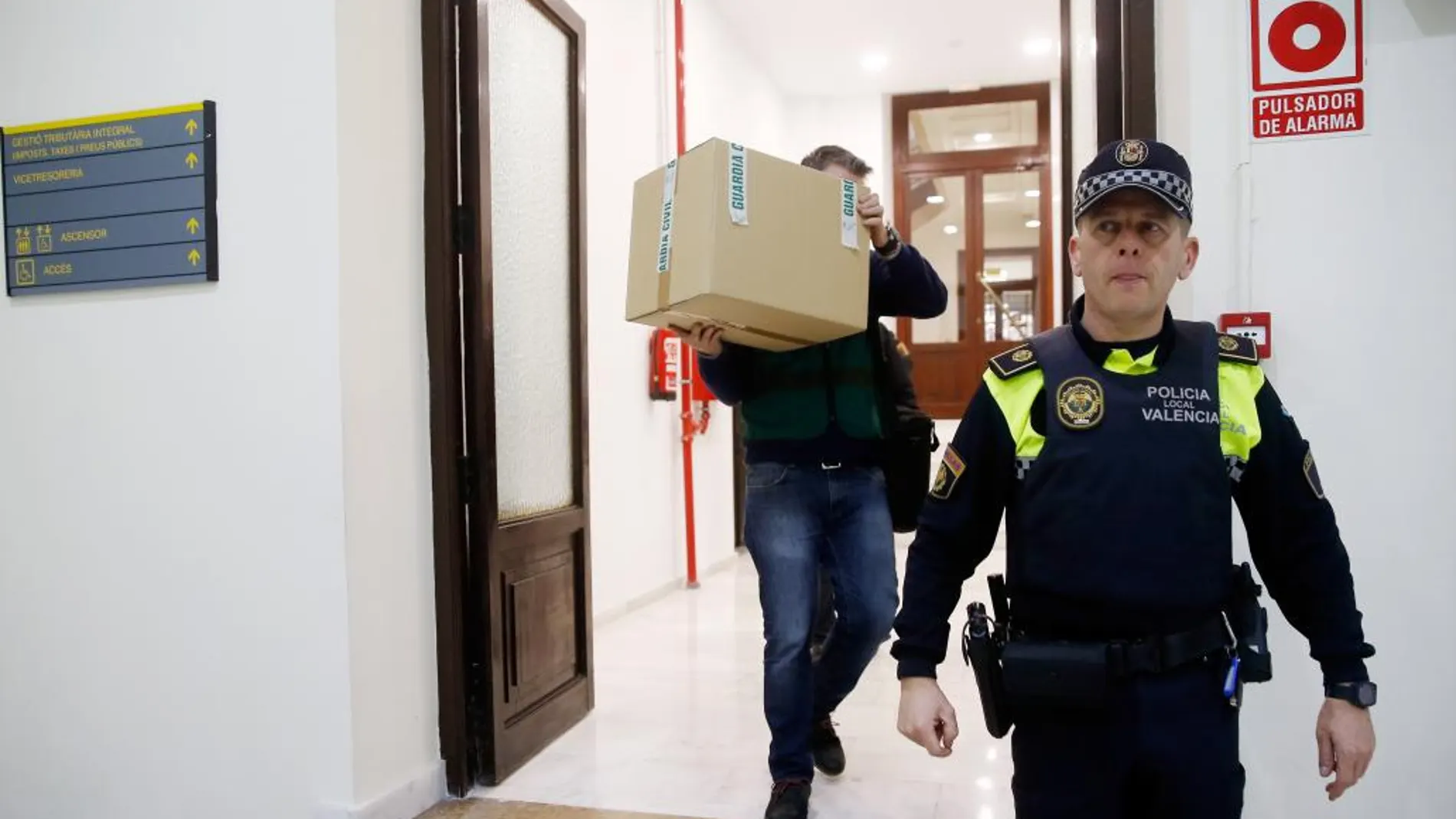 Un agente de la Guardia Civil lleva una caja con el material incautado en el registro de las oficinas del grupo municipal popular.