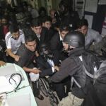 Rafael Correa, con máscra de gas, es evacuado en silla de ruedas del hospital por efectivos del ejército