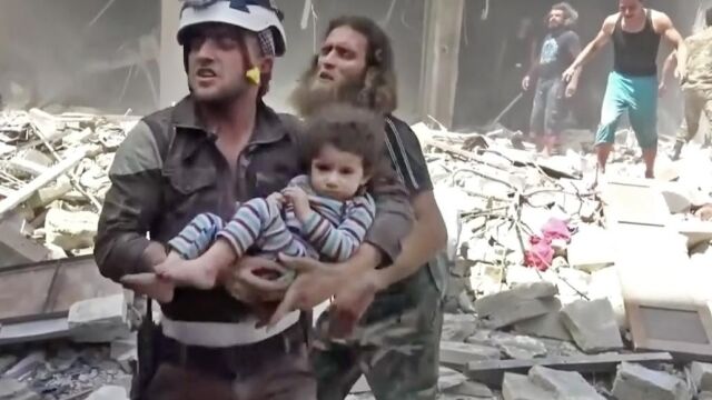 Un miembro de los equipos de rescate traslada a una niña