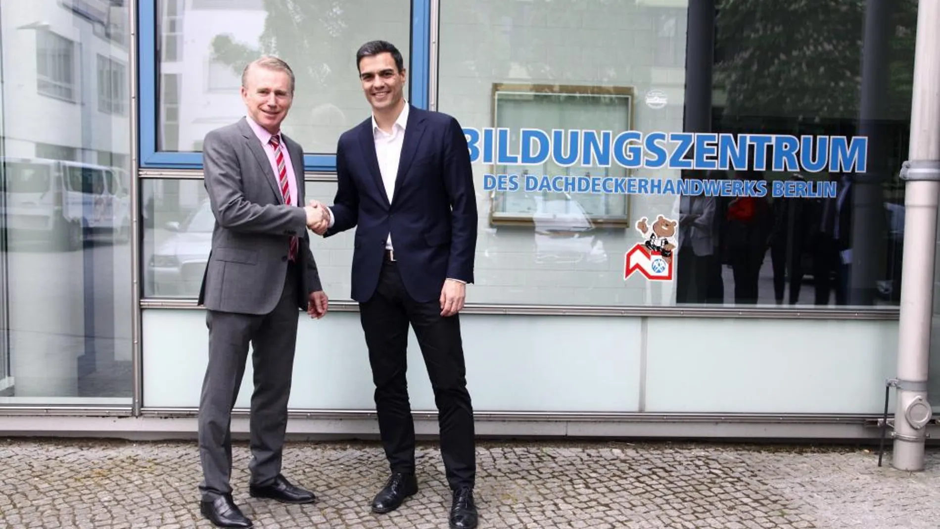 El secretario general del PSOE y candidato a la Presidencia del Gobierno, Pedro Sánchez (d) saluda al director del centro, Rudiger Thaler durante la visita a un centro en el que se imparte formación profesional para refugiados 'Landesinnung des Dachdeckerhandwerks Berlin'.