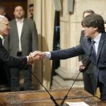 Raül Romeva (i), saluda al presidente de la Generalitat, Carles Puigdemont, tras tomar posesión de su cargo.