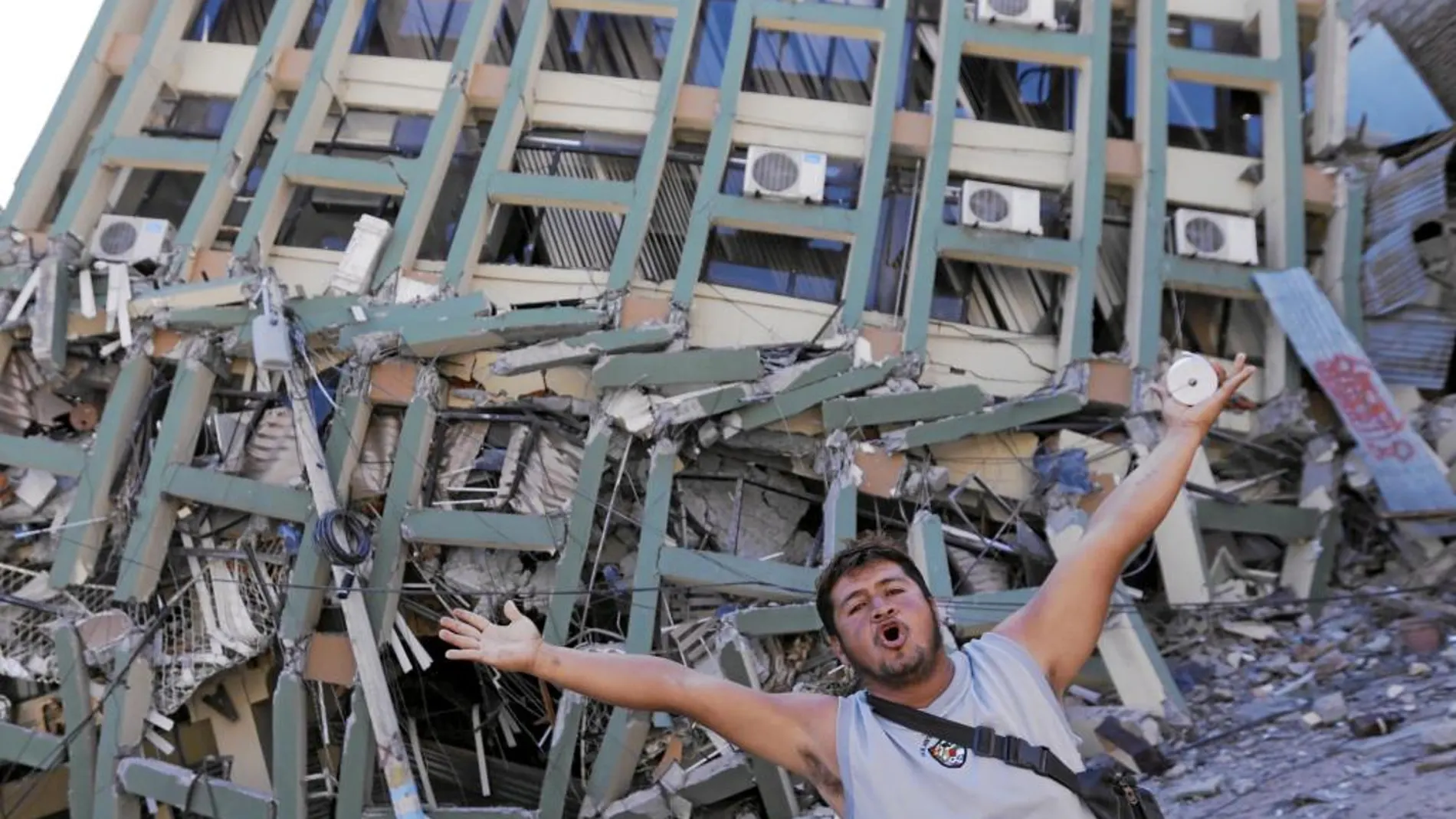 Un vecino de Portoviejo hace gestos en petición de ayuda frente a uno de los edificios desplomados por el seísmo
