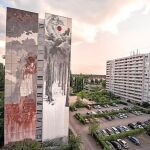 La obra de la polémica ocupa los 42 metros de una fachada. Junto a ella, un pájaro azul, obra en las antípodas de la de Borondo