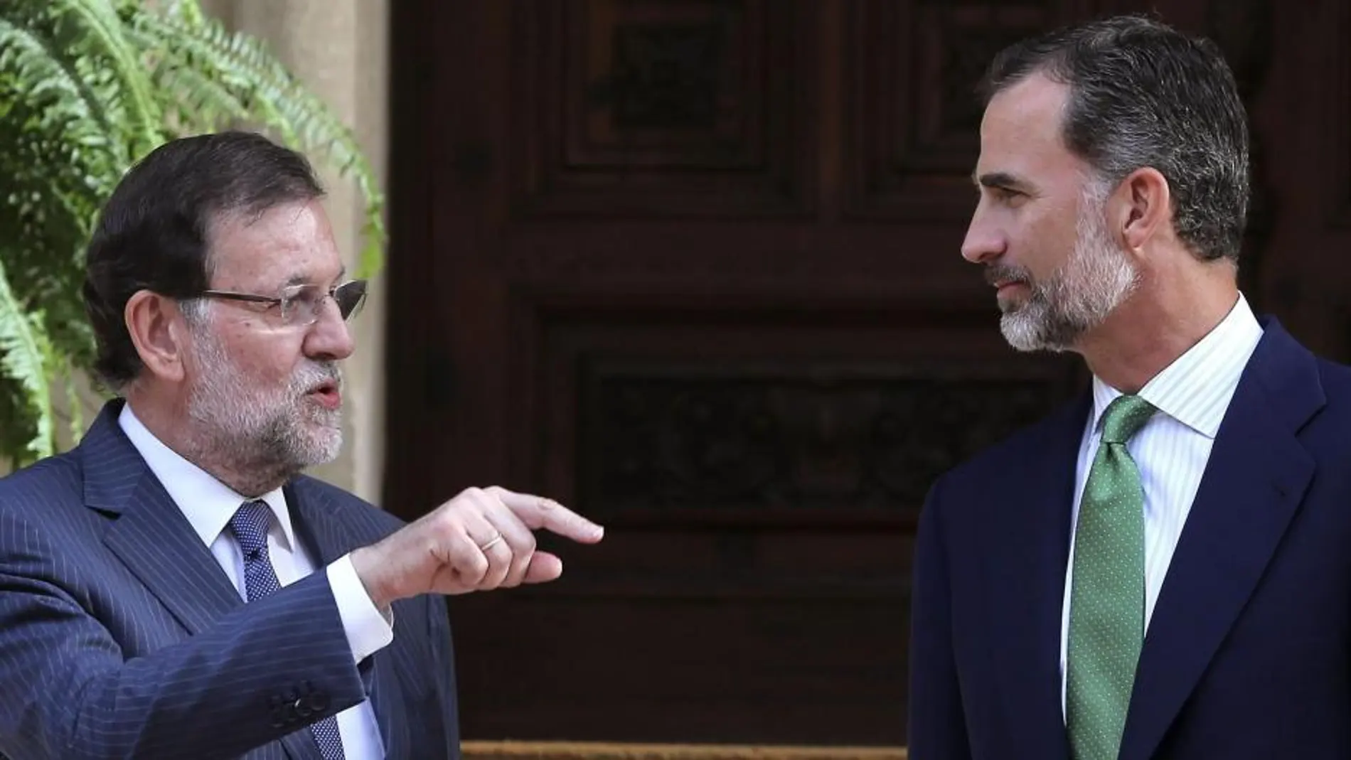 El presidente del Gobierno, Mariano Rajoy (i), conversa con el rey Felipe VI (d) a su llegada al Palacio de Marivent