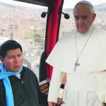 Un sacerdote boliviano viaja con una imagen a tamaño real del Papa en el teleférico que une La Paz con El Alto