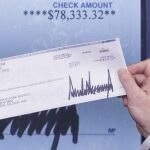 El secretario de Prensa de la Casa Blanca, Sean Spicer, sostiene un cheque donado por el presidente de Estados Unidos, Donald Trump
