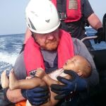 Un voluntario de Sea-Watch sostiene en brazos al bebé tras ser rescatado del mar.