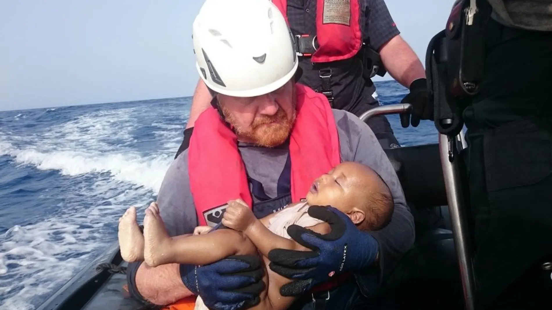 Un voluntario de Sea-Watch sostiene en brazos al bebé tras ser rescatado del mar.