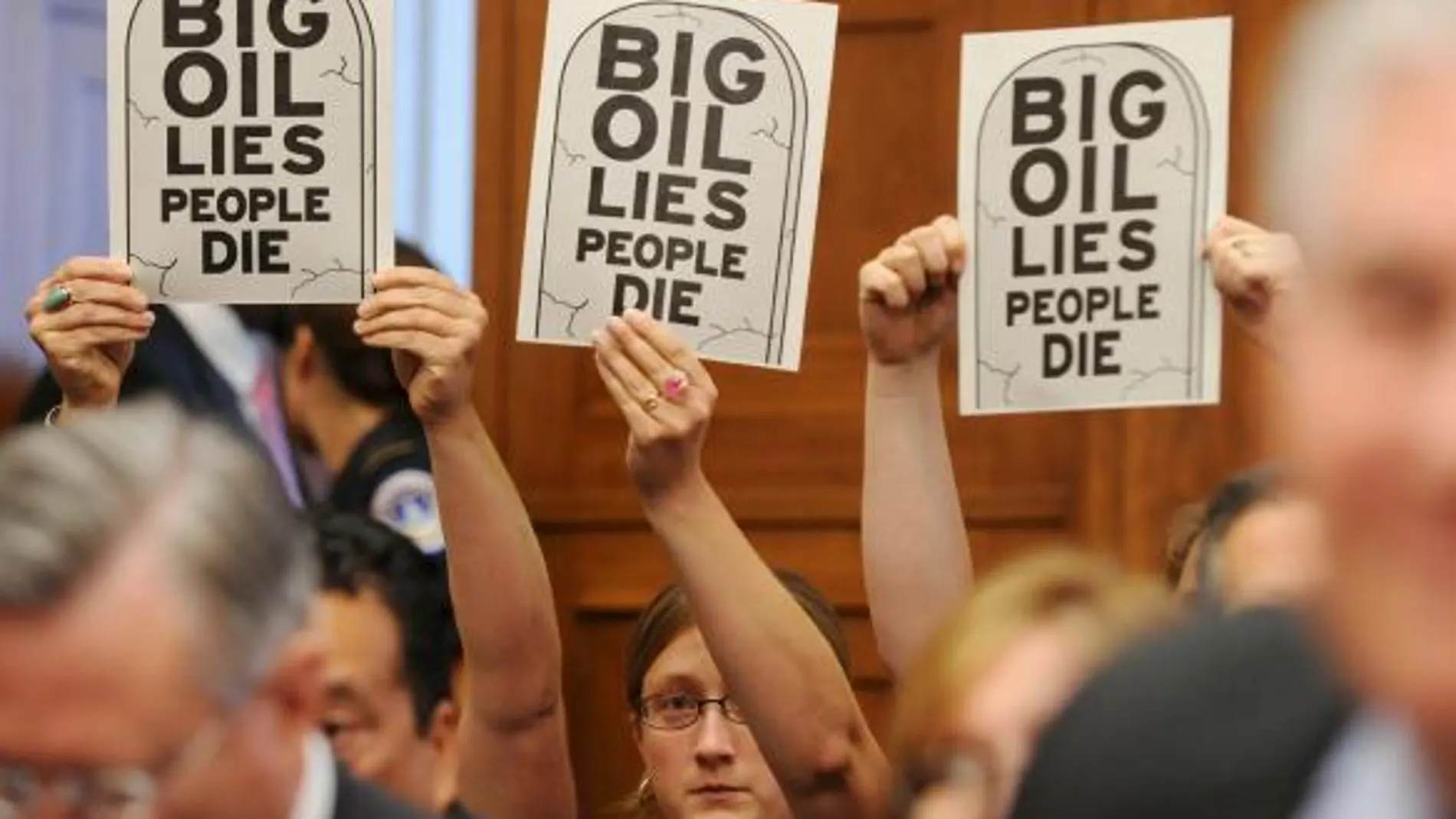 Unas personas sostienen unos carteles en los que se lee "La gran petrolera miente y la gente muere"durante la reunión del subcomité de Energía, Comercio y Medio Ambiente de la Cámara de Representantes