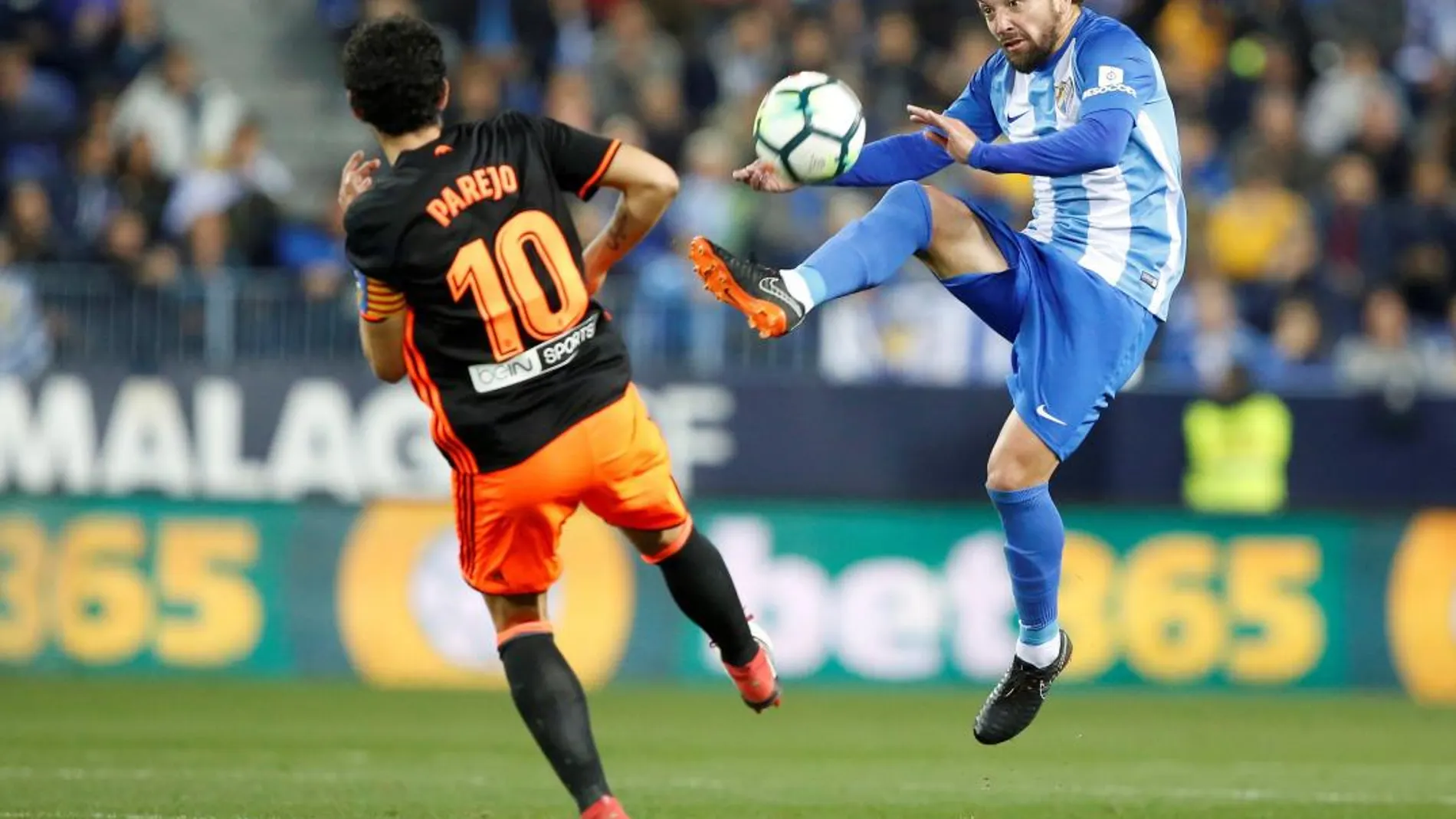 El centrocampista del Valencia CF Daniel Parejo (i) intenta robarle el balón al centrocampista del Málaga Manuel Iturra