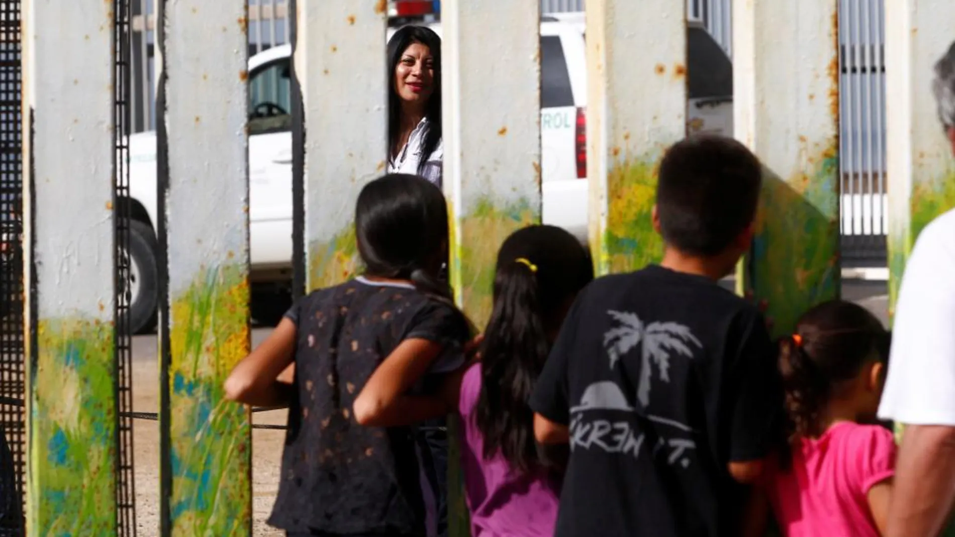 Una mujer habla, desde el lado de EEUU, con un grupo de niños mexicanos, separados por la vaya fronteriza que separa México de Estados Unidos