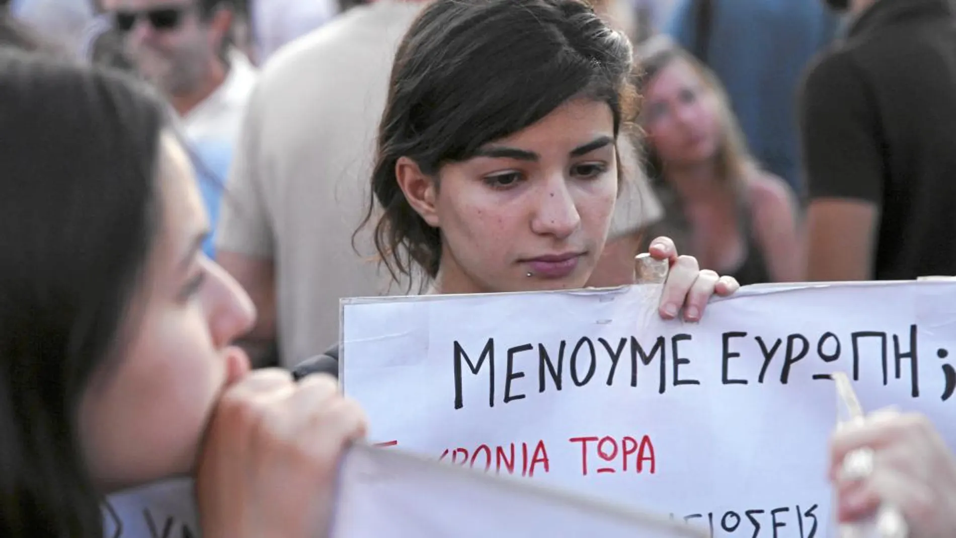 Una joven porta una pancarta ayer durante una manifestación antiausteridad en Atenas donde se pregunta: «Estamos en el euro»