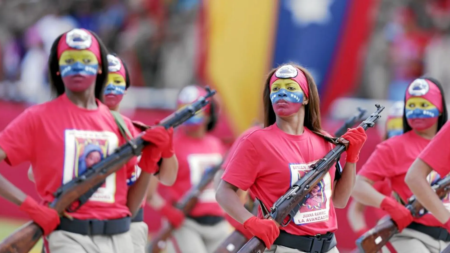 Mujeres con la cara pintada con los colores de la bandera venezolana, desfilan por el aniversario de la independencia