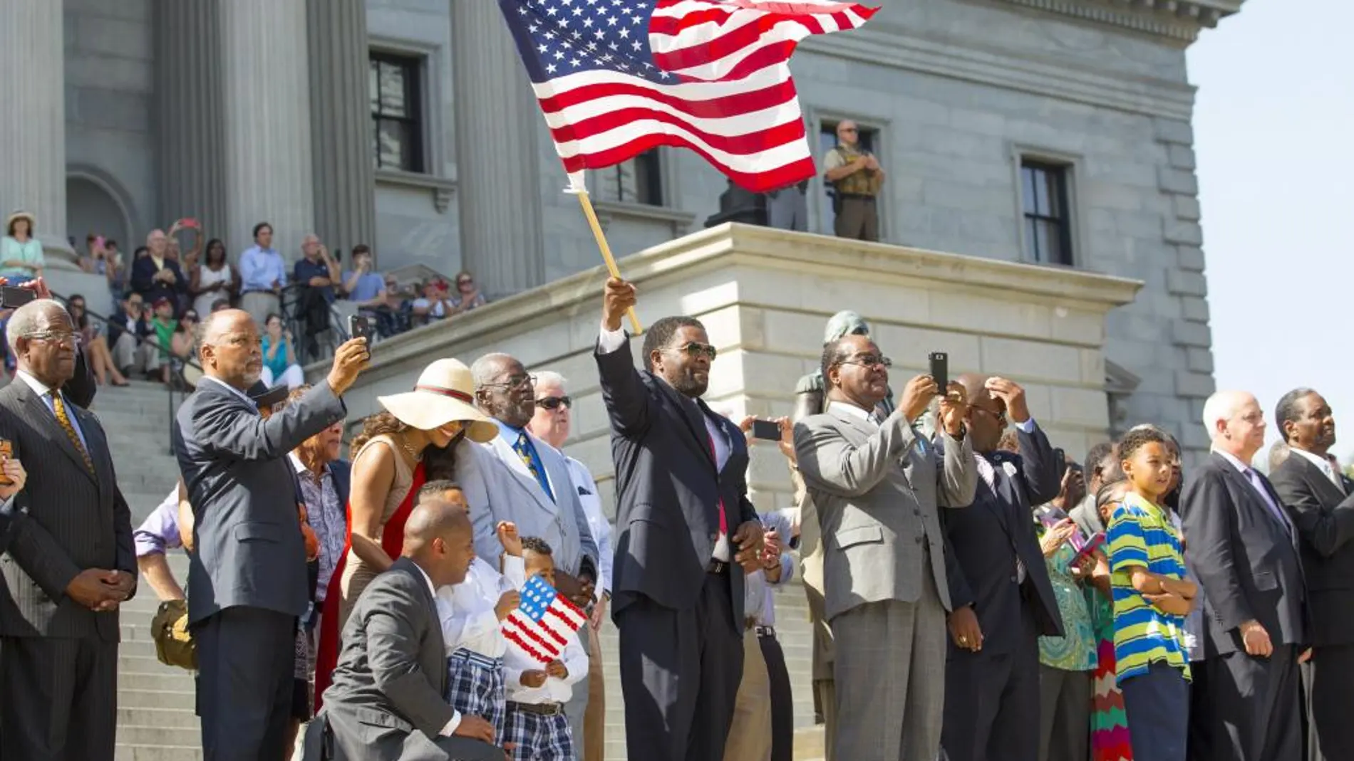 Un hombre ondea la bandera de Estados Unidos en el acto de retirada de la enseña confederada.