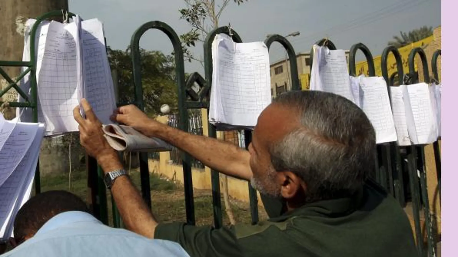 Dos votantes comprueban las listas en las puertas de un colegio electoral