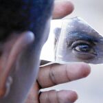 Un migrante usa un trozo de cristal como espejo en el puente de San Ludovico, en la costa Mediterránea entre Ventimiglia (Italia) y Menton (Francia)