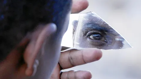 Un migrante usa un trozo de cristal como espejo en el puente de San Ludovico, en la costa Mediterránea entre Ventimiglia (Italia) y Menton (Francia)